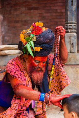 Pashupatinath, Nepal - 17 Temmuz 2018: Kutsal Sadhu adam geleneksel boyalı yüz ve colouful giysileri ile Pashupatinath, ünlü ve Kutsal Hindu Tapınağı Nepal'de karmaşık bir çocuğa nimet