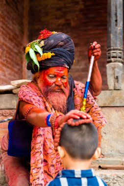 Pashupatinath, Nepal - 17 Temmuz 2018: Kutsal Sadhu adam geleneksel boyalı yüz ve colouful giysileri ile Pashupatinath, ünlü ve Kutsal Hindu Tapınağı Nepal'de karmaşık bir çocuğa nimet