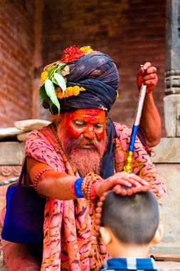 Pashupatinath, Nepal - 17 Temmuz 2018: Kutsal Sadhu adam geleneksel boyalı yüz ve colouful giysileri ile Pashupatinath, ünlü ve Kutsal Hindu Tapınağı Nepal'de karmaşık bir çocuğa nimet