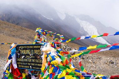Annapurna koruma alanı, Nepal - 28 Temmuz 2018: Bilgi işareti ve dua bayrakları Thorang-la geçişte, Annapurna devre, Annapurna koruma alanı, en büyük koruma alanı Nepal