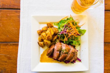 Arka planda soğuk bira ile ördek meme ve patates yemek yakın çekim