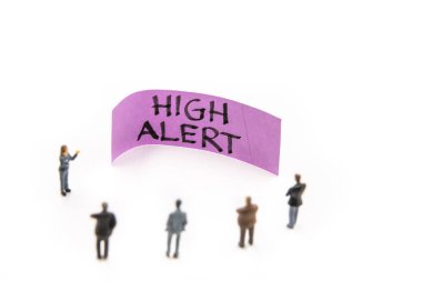Minyatür heykelciklerle yapılan strateji toplantısı, beyaz arkaplan üzerine Yüksek Alarm mesajı, metin odaklı minimalist soyut kavram ve yüksek uyarı notu etrafında duran iş adamları gibi gösterildi.
