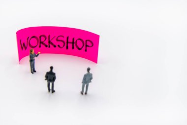 Minyatür heykelciklerle yapılan sunum toplantısı, atölye notunun önünde duran iş adamları gibi görünürken, arka planda el yazısıyla yazılmış mesaj, sağda kopyalama alanı