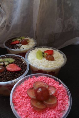 Taze meyve salatası kavun, üzüm, çilek yoğurt kaplı kivi. Üstü için peynir ve meyve. Ahşap tepside kare plastikle servis ediliyor. seçici odak