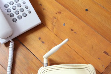 Kablosuz modem ve ahşap masadaki telefon yakın plan.