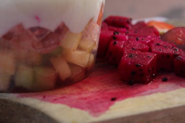 Taze meyve salatası kavun, üzüm, çilek yoğurt kaplı kivi. Üstü için peynir ve meyve. Ahşap tepside kare plastikle servis ediliyor. seçici odak