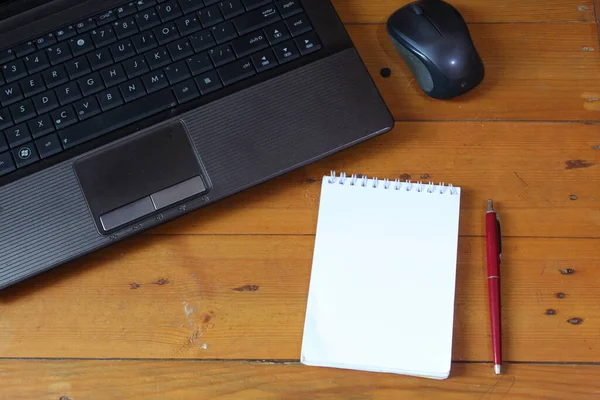 Hand is holding pen and writing in the notebook. Tablet, calculator on the desk. Home office concept. work from home