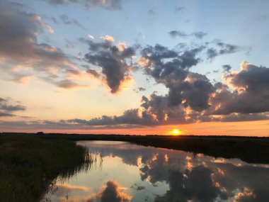 gün batımında güneş batıyor bulutlar göle yansır
