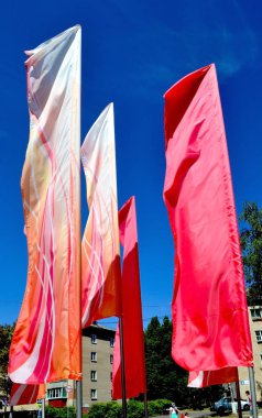 Rüzgara karşı mavi gökyüzü içinde çırpınan parlak, neşeli kırmızı ve pembe bayrak