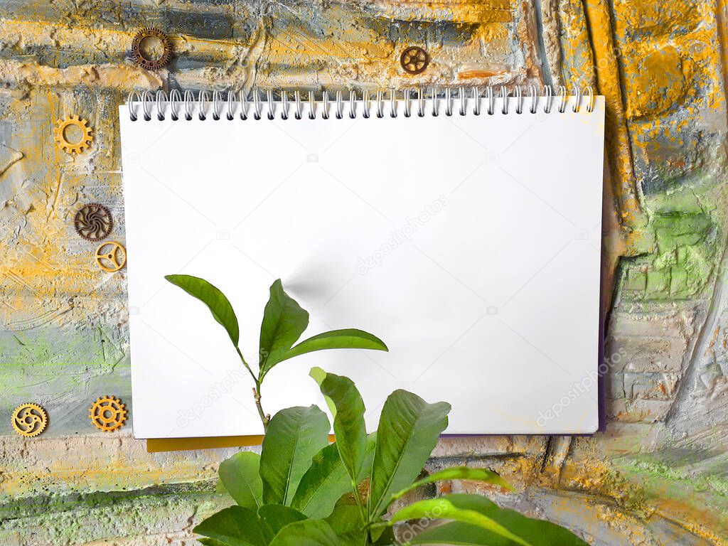 notepad on a color wall with a plant and gears