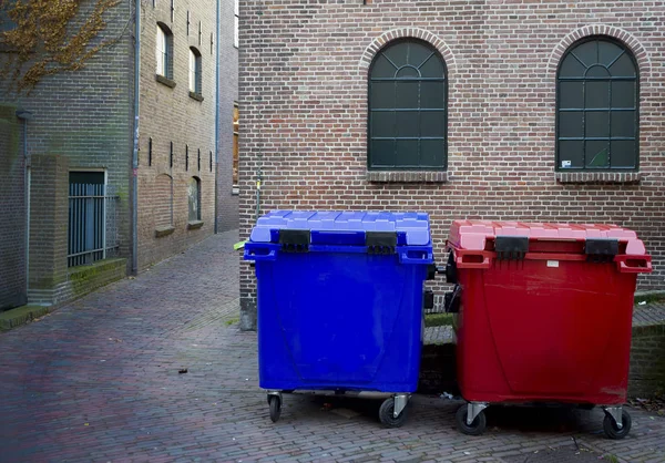 Red and blue waste bins with red brick wall in the background