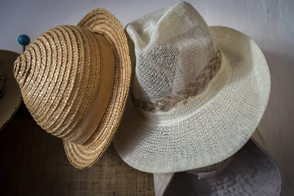 Straw hats hanging on a white-painted wall