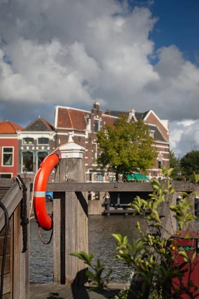 Cinturón de seguridad naranja colgado en el peer de madera cerca del canal en Lei —  Fotos de Stock