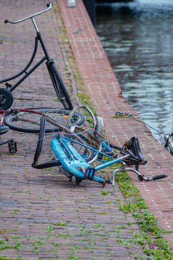 Terk edilmiş mavi bisiklet kıyıda, kanalın yanında.
