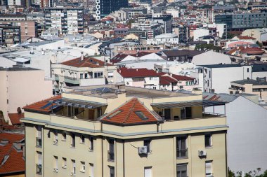 Belgrad ve Sırbistan 'ın yoğun kentsel manzarası, parlak gün ışığında kırmızı ve kahverengi çatıları, balkonları, pencereleri ve klimaları olan apartman blokları ve konut binalarını gösteriyor.
