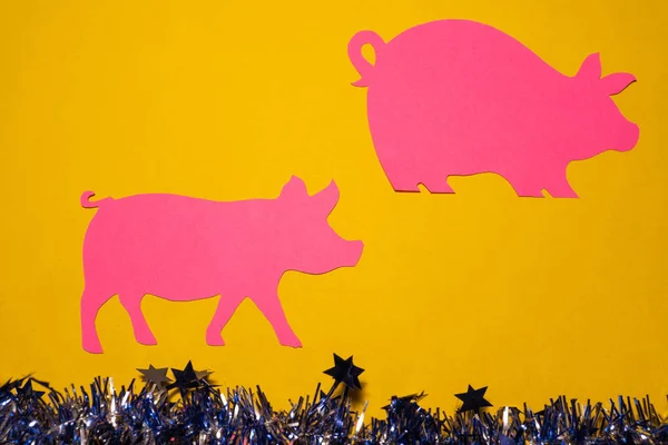 Christmas composition. pink pigs on yellow background with space for text