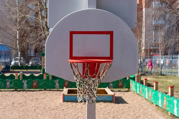 basketball Hoop with a net on a white shield on the street.