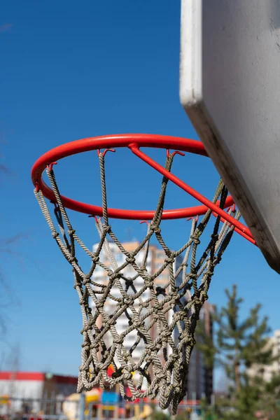a basketball Hoop with a net in the street on the background of blue sky
