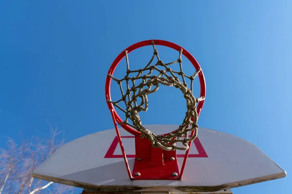 a basketball Hoop with a net in the street on the background of blue sky. bottom view