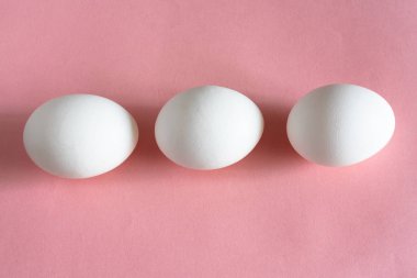Pembe pastel arka planda beyaz tavuk yumurtası. Paskalya için tasarım ve dekor