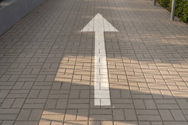 Asfalt döşeme yolundaki beyaz ok, yönü gösteriyor