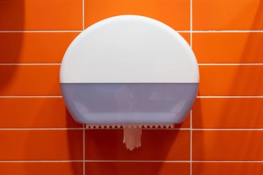 Turuncu duvarda beyaz plastik tuvalet kağıdı. Yakın plan.