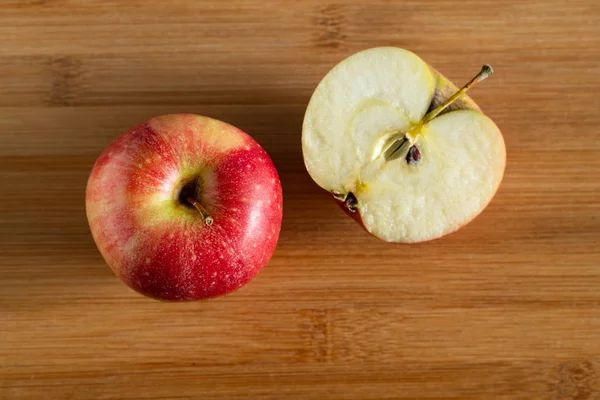 Одно целое яблоко с половиной яблока на деревянном фоне — стоковое фото