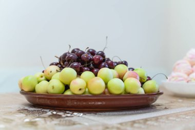 Taze meyveler ve meyveleri olan bir tabak. Tatlı kiraz, kayısı, şeftali ve nektarinler.
