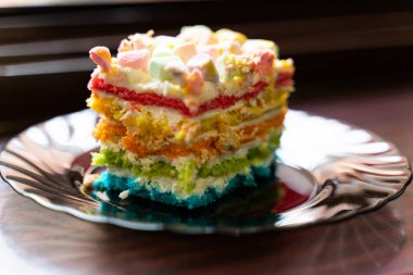 renkli krema ile kek bir parça bir tabak üzerinde marshmallow spişile serpilir