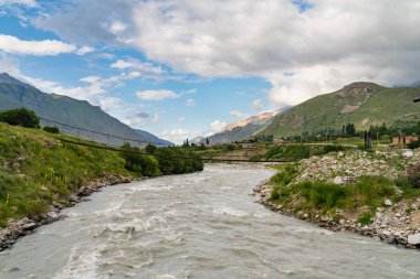 Güzel manzara, dağ vadisindeki çalkantılı nehrin üzerindeki eski köprü.