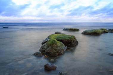 taşlar ve mavi gökyüzü bulutlu moss ile okyanus plaj büyümüş
