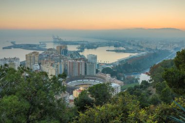 İspanyol şehir Malaga gün batımında. Liman ve yukarıdan bir boğa yüzük ile eski şehir. Yapı ve gemi limanda görülebilir. deniz ve dağlar görmek için arka planda olduğunu