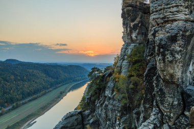 Sakson İsviçre Ulusal Parkı içinde Elbe Nehri üzerinde gün batımı. Ağaçlar ve ormanlar, nehir Elbe kumtaşı dağlarda kaya oluşumu.