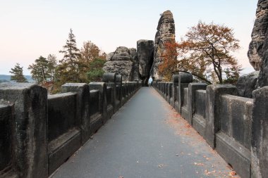 Üst ders ve patika Sakson İsviçre Ulusal Parkı Bastei Köprüsü. Elbe kumtaşı Dağları. Kaya oluşumu ve ağaçlar sonbahar ruh hali ile kayalık kapı görünümünü