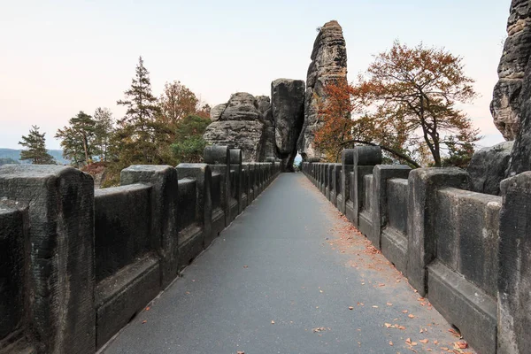 Upper course and footpath of the Bastei bridge in the national park Saxon Switzerland. Elbe sandstone mountains. View of rock formation and rocky gate with trees in autumn mood