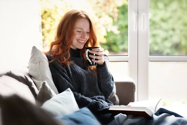 Belle Rousse Femme Blotti Sur Canapé Lecture Livre Tout Tenant Image En Vente