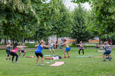Moskova, Museon Park, 14 Temmuz 2018: Grup yeşil yaz Park erkek Koç ile fiziksel egzersizleri yapıyor spor giyim kadın ve adam. Spor açık havada.