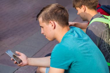 Moskova, Arbat Sokağı, 8 Eylül 2018: iki arkadaş bir bankta oturan bir smartphone, medya içeriklerinde izlerken