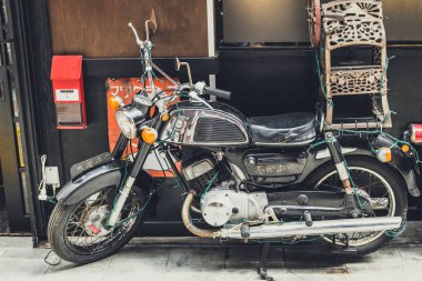 Japonya, Beppu, 18 Eylül 2017: eski, paslı motosiklet Suzuki 125 ayakta duvara. Tonda.