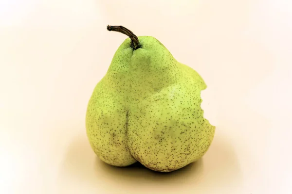 Pera verde primer plano sobre fondo beige. La forma inusual de la fruta . — Foto de Stock