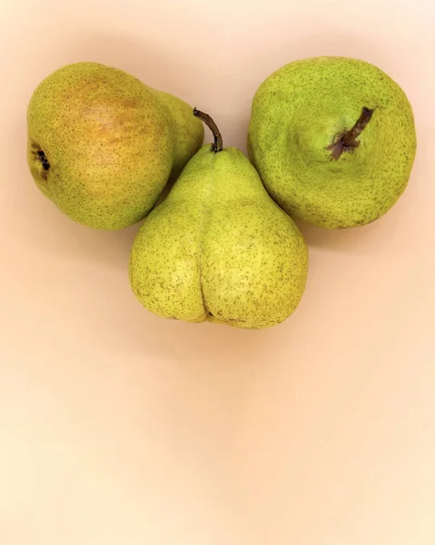 Bej arka planda üç yeşil armut yakın çekim. Meyvenin alışılmadık şekli.