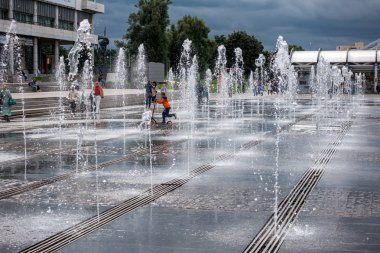 Su fıskiyelerinin arasında scooter süren küçük bir çocuk.