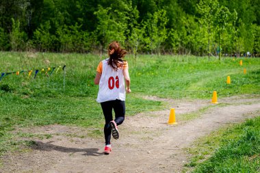 Genç bir kadın doğada koşmakla meşgul.
