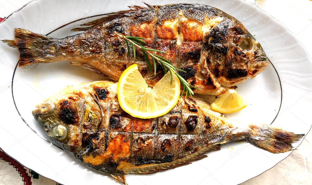 Grilled fish, sea bream, dorada on the plate with lemon slice