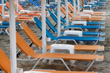 Turuncu ve mavi plaj sandalyeleri ve düzenlenmiş tablolar