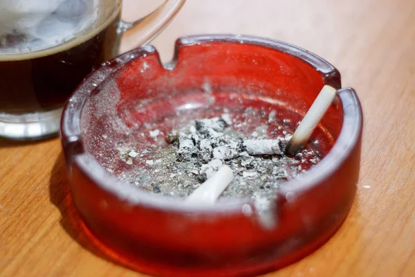 Askkopp med brända cigaretter bredvid en kopp kaffe — Stockfoto