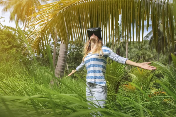 Virtual reality VR 3D headset and woman exploring the play on a background of nature jungle
