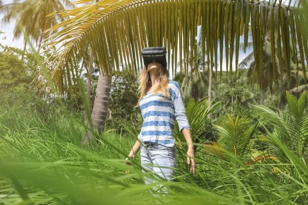 Virtual reality VR 3D headset and woman exploring the play on a background of nature jungle