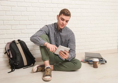 Genç adam ders kitapları ile katta oturuyor.