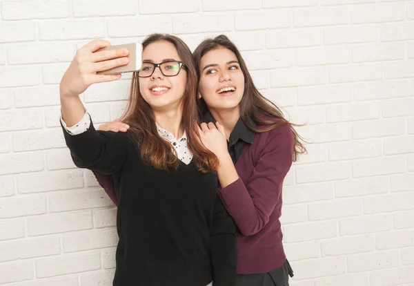 Girls teenagers against a white brick wall — Stock Photo, Image